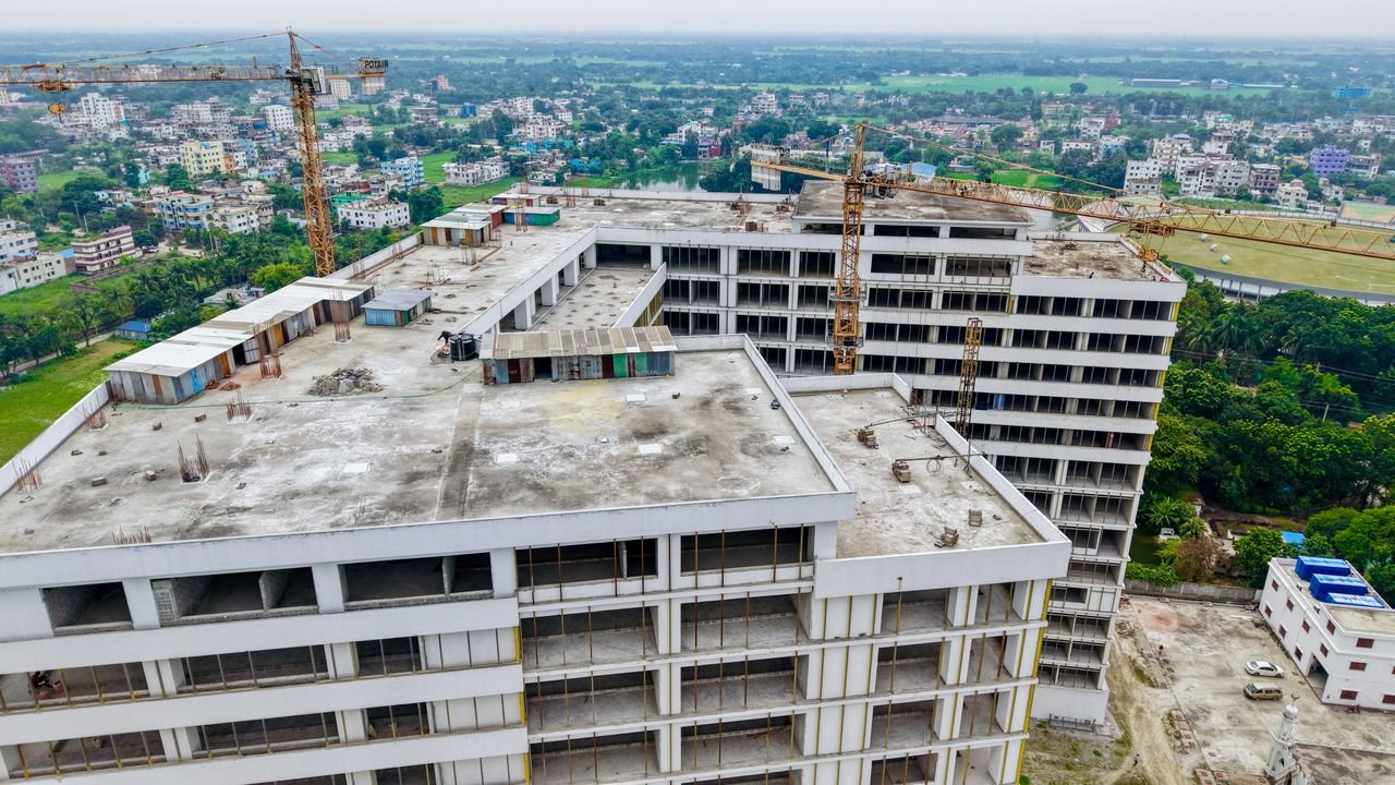 High-rise building under construction in an urban setting with prominent cranes.