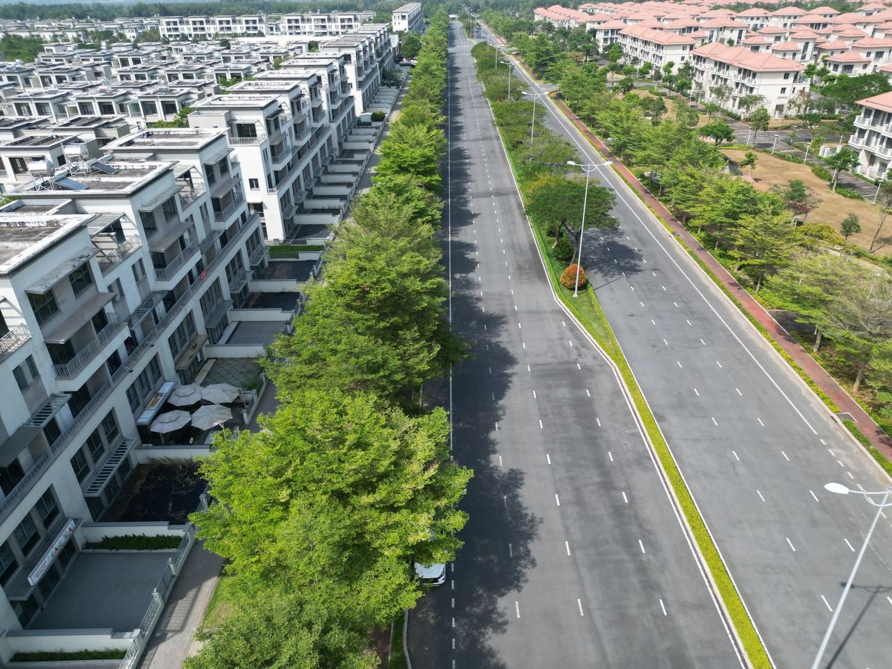 Wide aerial view of luxury residential housing in Dong Nai, Vietnam showcasing modern architecture along an empty road.