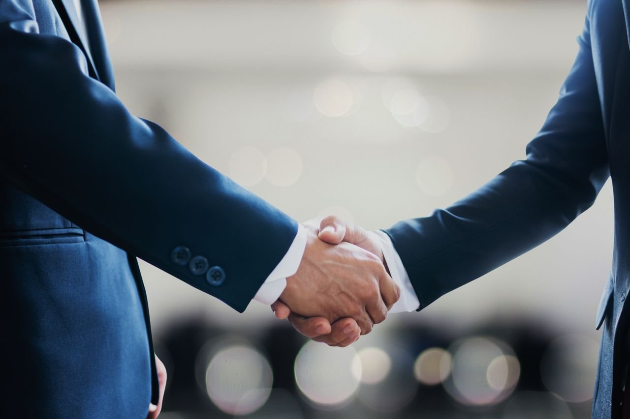 Close-up of business professionals in suits shaking hands, symbolizing a successful collaboration or agreement.